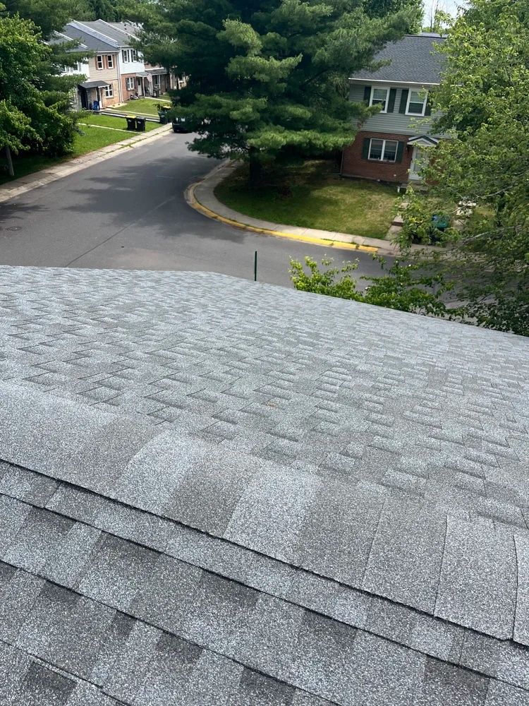 Gray shingle roof overlooking a quiet suburban street with houses and trees