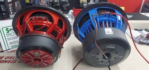 Two subwoofers, one red and one blue, sit side by side.