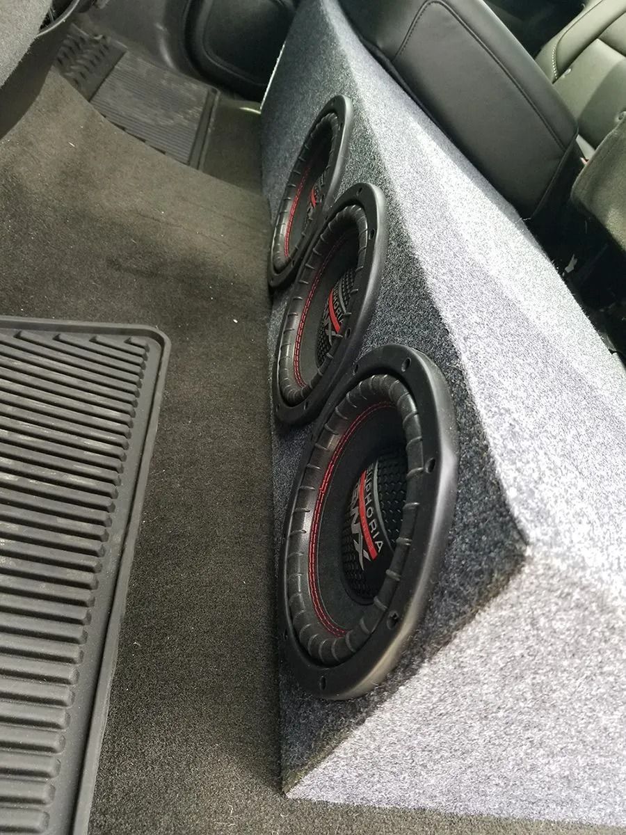 Three subwoofers in a custom gray speaker box installed in a vehicle.