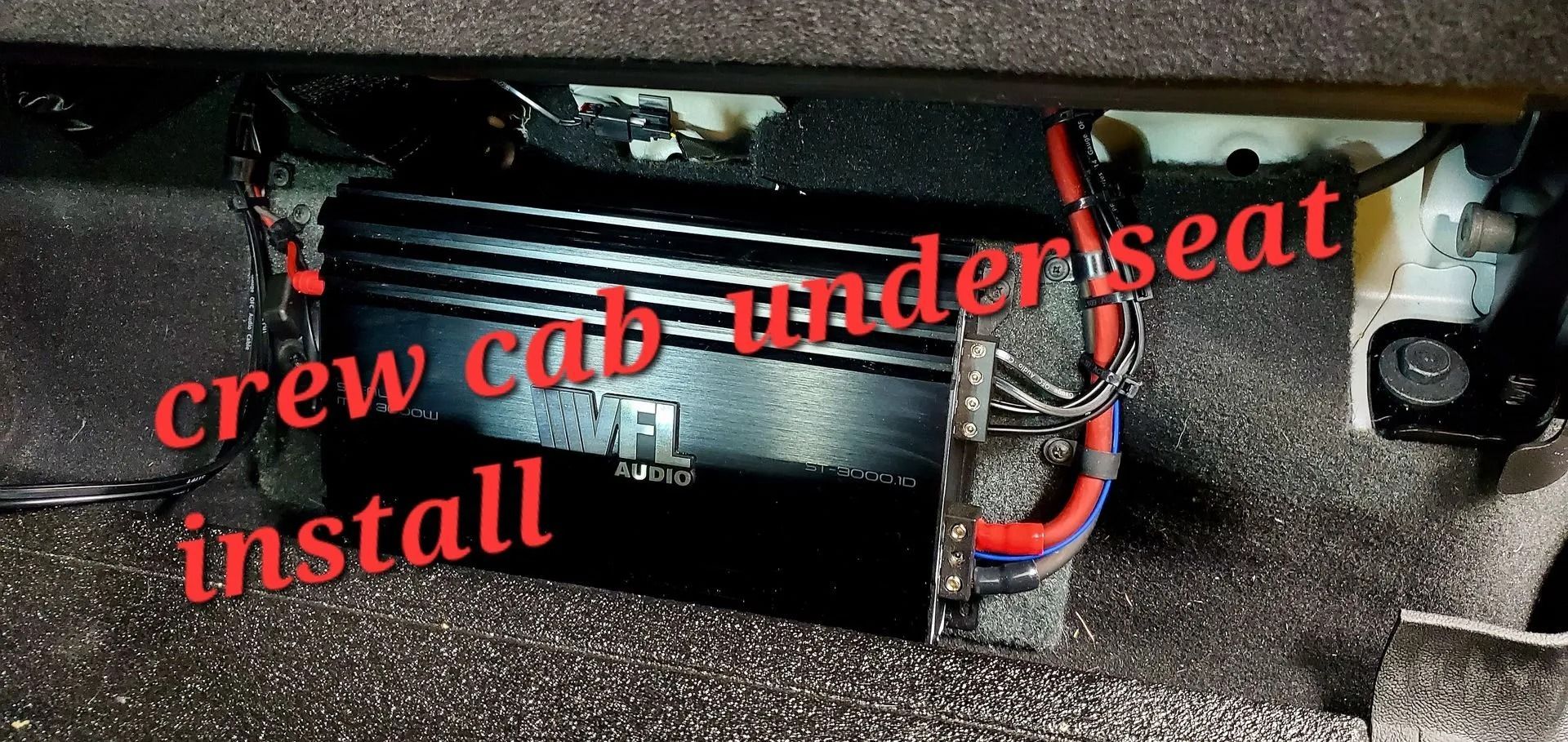 Car audio amplifier installed under the seat of a crew cab, with wires attached.