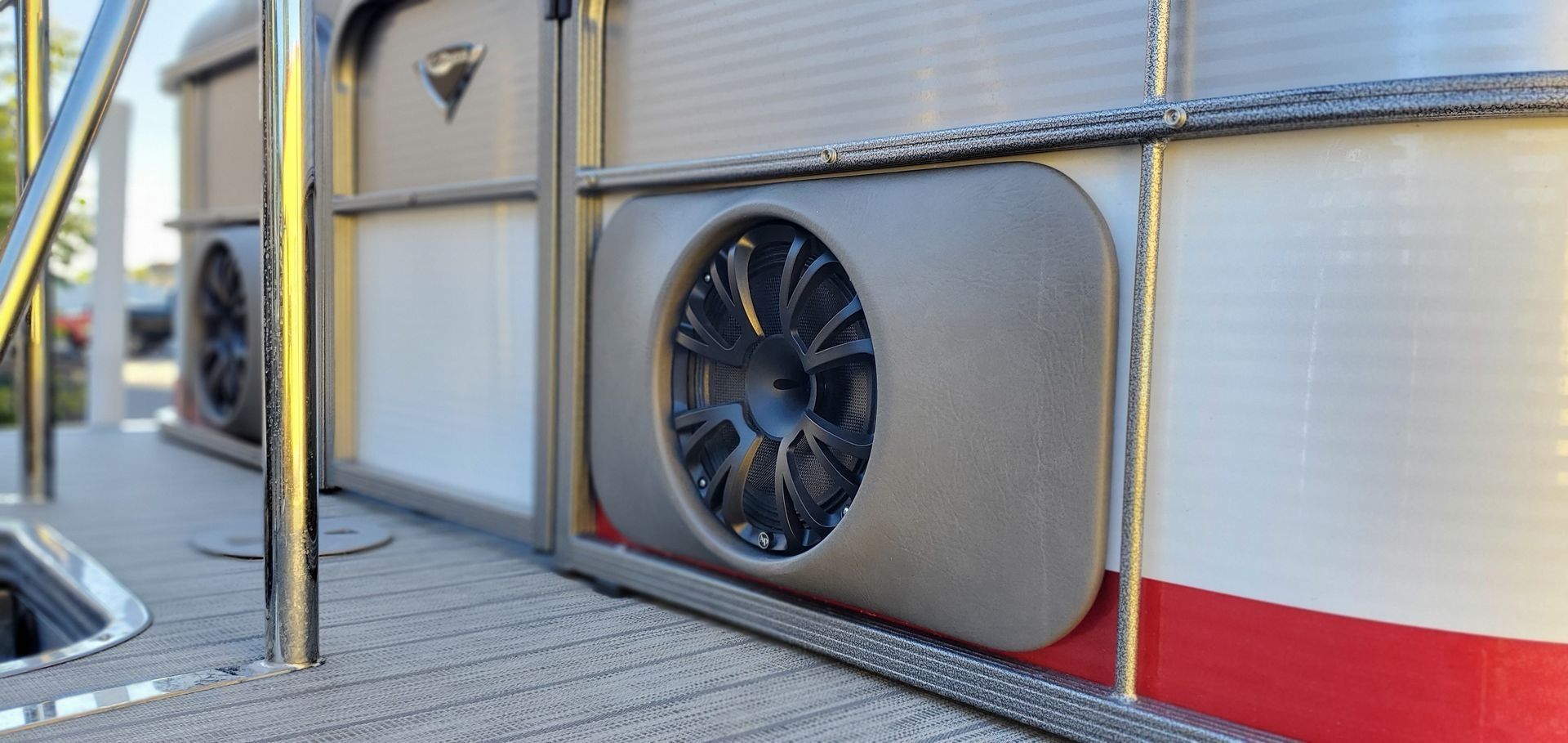 Close-up of a pontoon boat side with a speaker and railing.