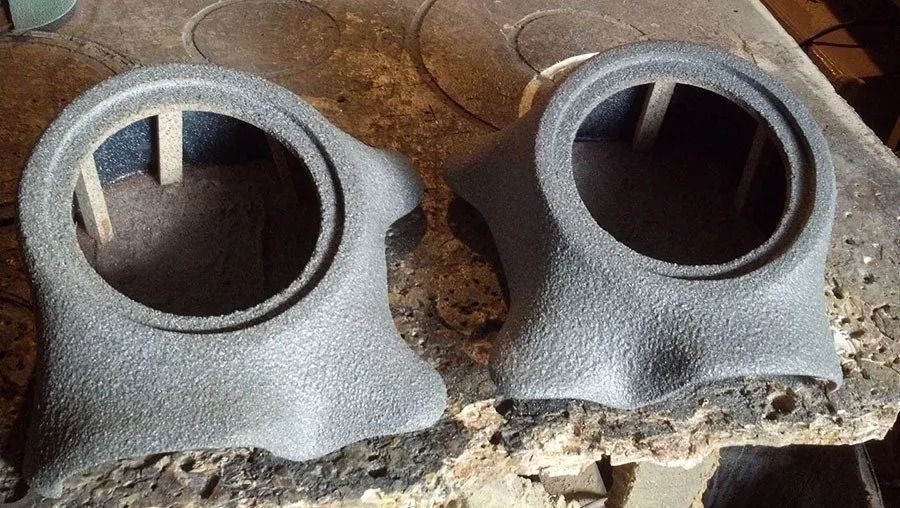 Two textured grey speaker enclosures with round openings.