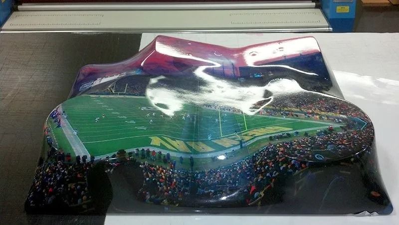 A custom printed object showing a stadium from above, distorted and reflecting light.