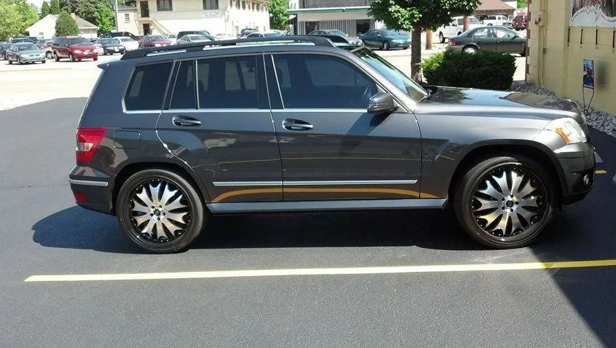 Dark gray SUV with tinted windows and custom silver and black rims parked outside a building.
