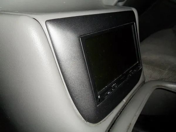 Gray car console with a rectangular screen in a metallic frame.