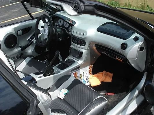 Silver and black car interior with custom dashboard and seats; open top.
