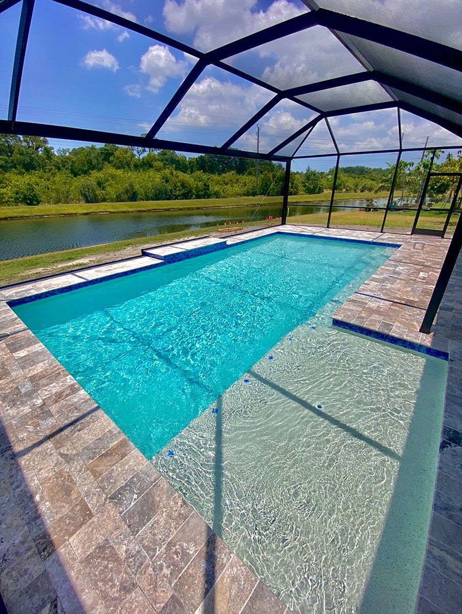 A large swimming pool with a screened in area and a view of a lake.