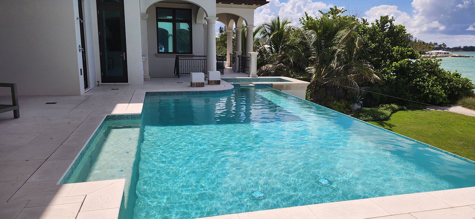 There is a large swimming pool in front of a house.