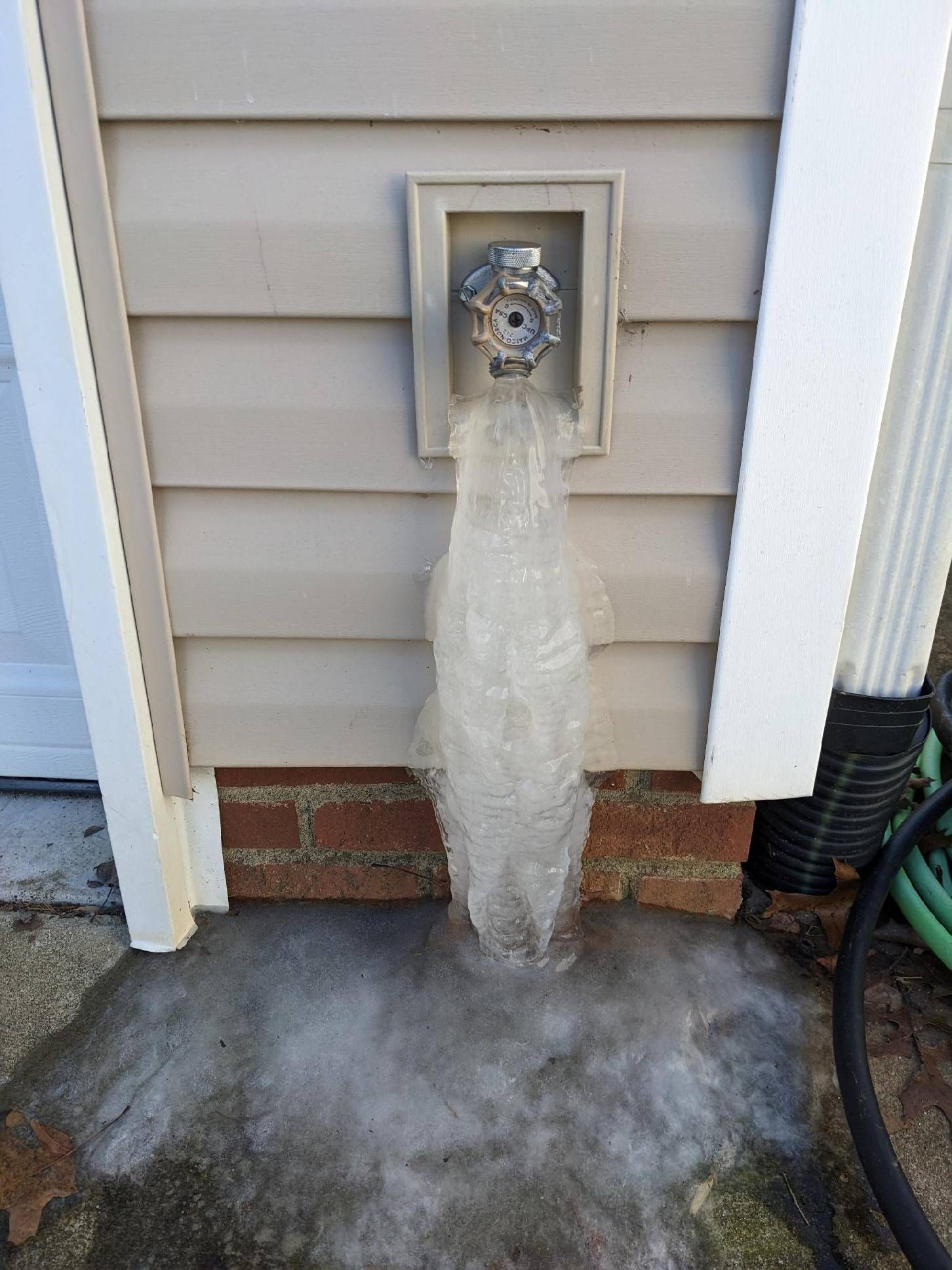 A frozen water faucet on the side of a house