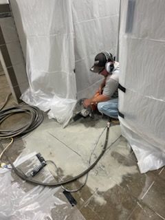 a man is kneeling on the floor using a grinder