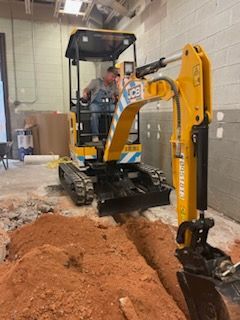a man is driving a small yellow excavator in a building