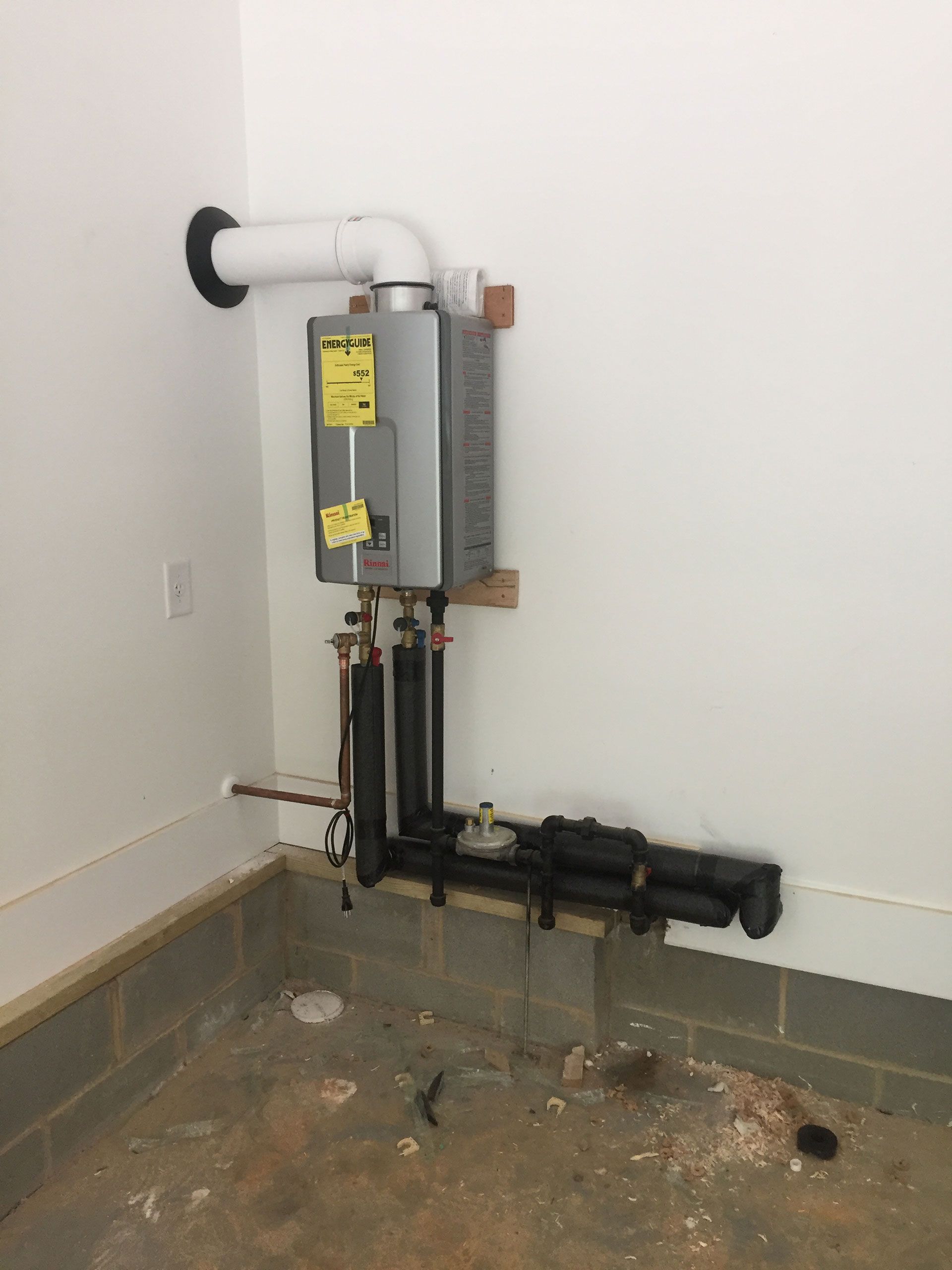 A room with a water heater and pipes on the wall