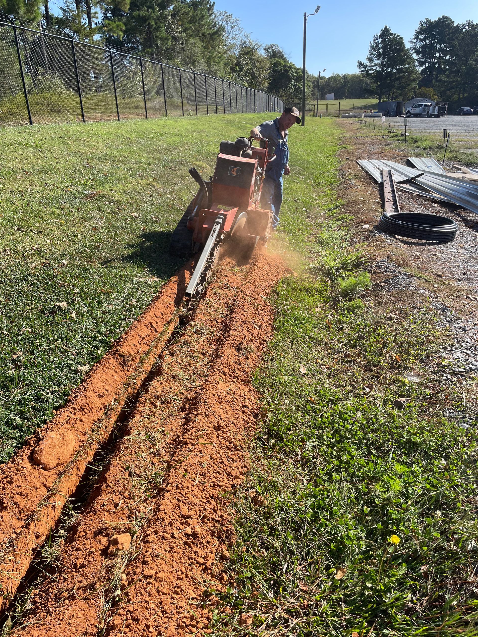 Using a trencher to dig a hole in the ground .