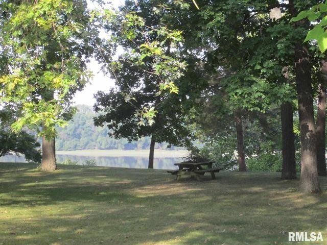A picnic table in a park with trees and a lake in the background