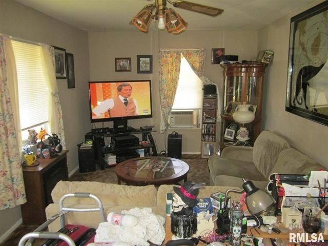 A living room with a flat screen tv and a ceiling fan