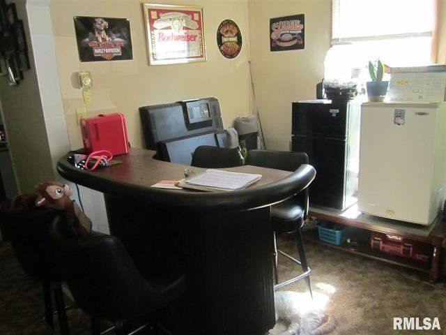 A room with a table and chairs and a refrigerator.