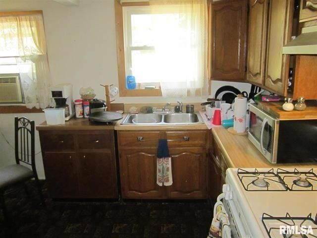 A kitchen with a stove a sink and a microwave