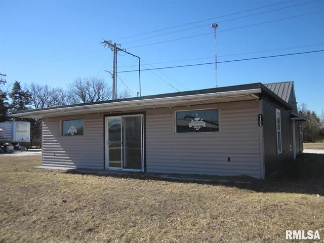 Blue and white ranch-style house with a single-car garage. Brown grass in the front yard. Bare trees in the background.