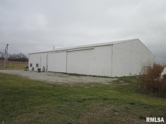 A large white building is sitting in the middle of a grassy field.