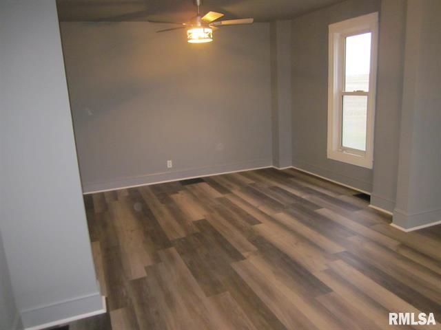 An empty room with hardwood floors and a ceiling fan.
