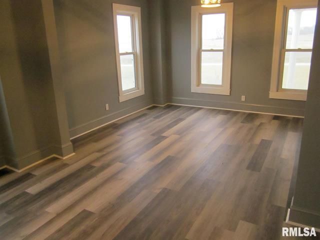 An empty room with hardwood floors and two windows