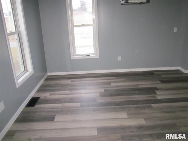 An empty room with hardwood floors and gray walls.