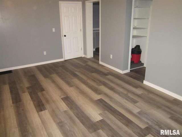 An empty room with hardwood floors and a rmlsa sign on the wall