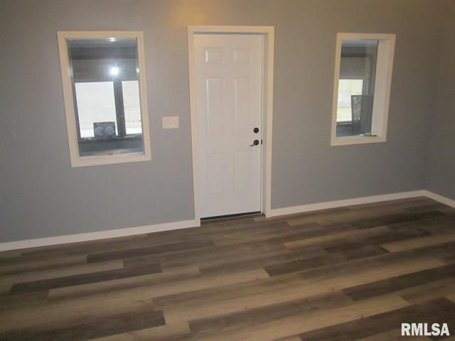 An empty room with hardwood floors and a white door.