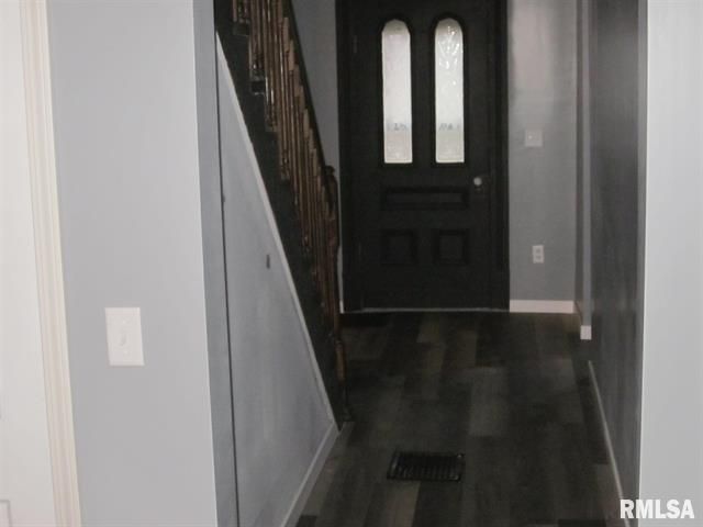 A hallway with a black door and stairs in a house.