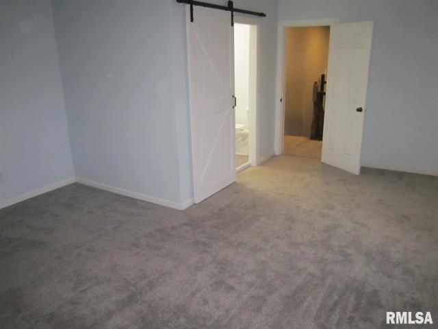 A bedroom with a sliding barn door leading to a bathroom