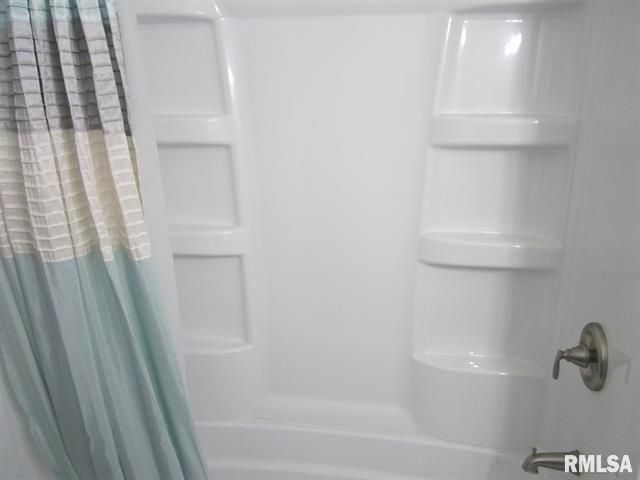 A shower stall with a shower curtain and shelves in a bathroom.