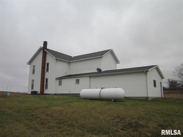 A large white house with a propane tank in front of it