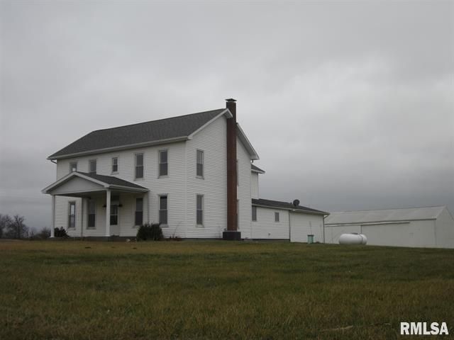 A large white house sits in the middle of a grassy field ..