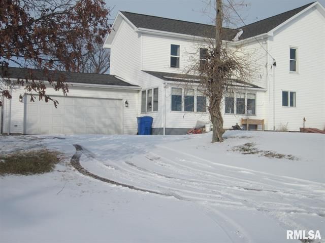 A white house with a black roof is covered in snow
