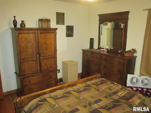 Bedroom with wooden furniture: armoire, dresser, bed, decor. Light walls, beige bedspread.