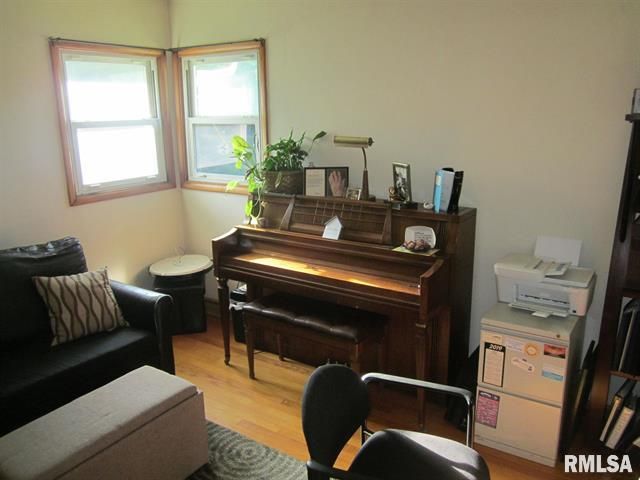 Living room with piano, black sofa, and light from two windows.