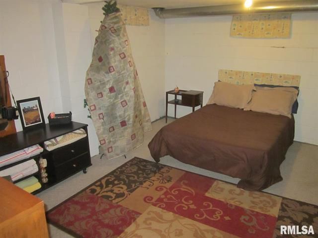 Bedroom with bed, dresser, nightstand, rug, and partially covered Christmas tree.