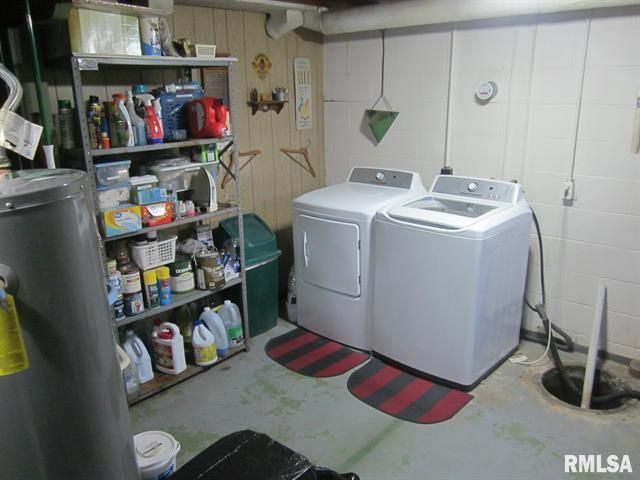 Laundry room with washer, dryer, storage shelves, water heater, and trash can.