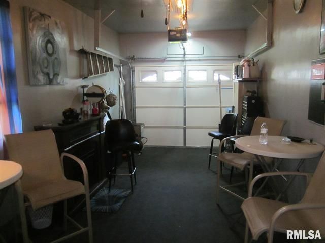 Garage converted to a bar. Includes barstools, round tables, and a garage door.