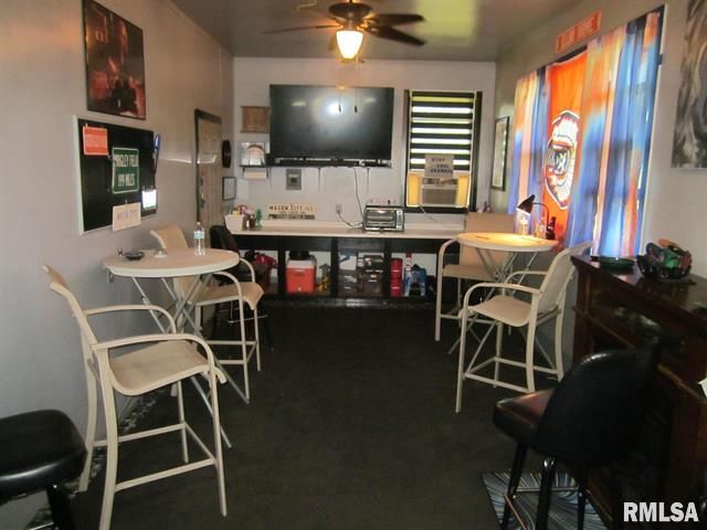 Interior view of a small bar with seating, a TV, and sports-themed decor.