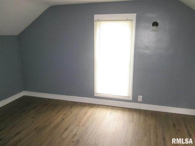 Empty room with dark gray walls, white trim, a window, and wood-look flooring