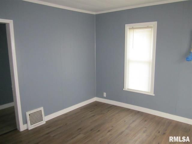 Empty room with gray-blue walls, white trim, wood-look flooring, and a window