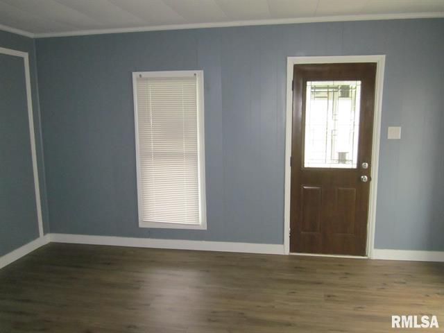 Empty room with blue walls, white trim, a brown door with glass