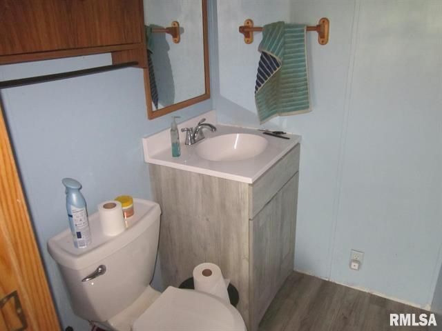 Bathroom with toilet, sink, mirror, and towel. Blue walls and light gray cabinet
