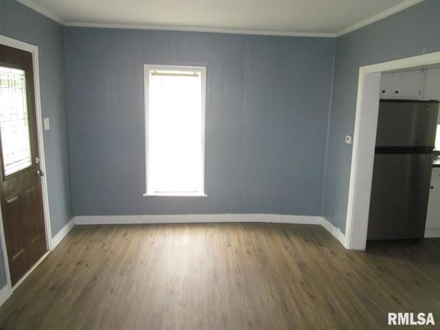 Blue-walled room with wooden floor. Window, door