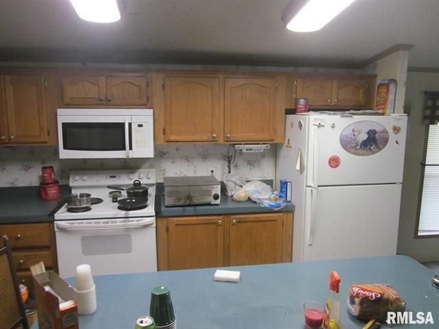 Kitchen with light brown cabinets, white appliances, and blue countertop