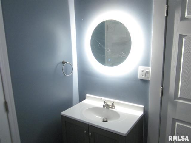 Bathroom with a blue wall, a round lighted mirror