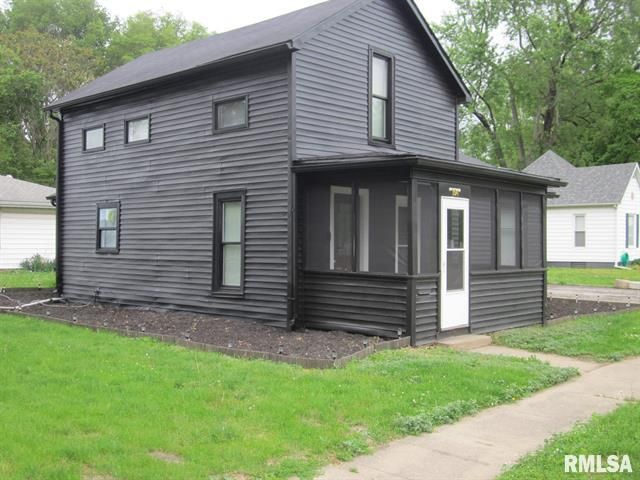 Black two-story house with a screened porch on a green lawn, sidewalk in front