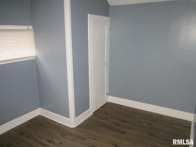 Empty room with blue walls, white trim, and brown flooring