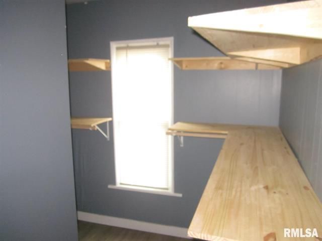 Empty room with built-in wooden shelves and a window